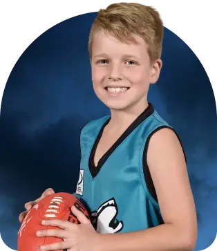 Young football player in a teal uniform holding a red football against a blue background.