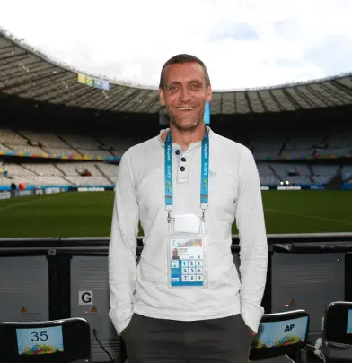Brandon Malone standing in a stadium wearing an event pass and smiling at the camera.